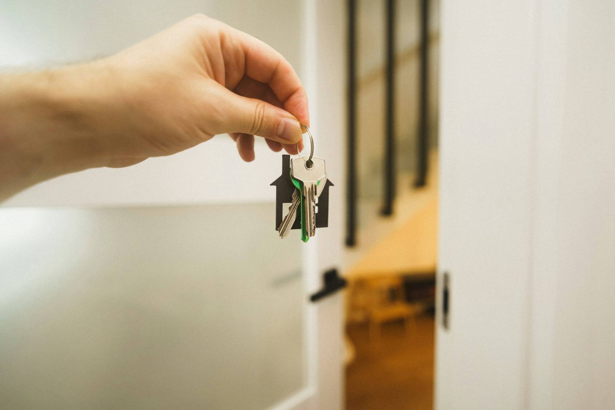 Mano che porge le chiavi di casa davanti a una porta aperta